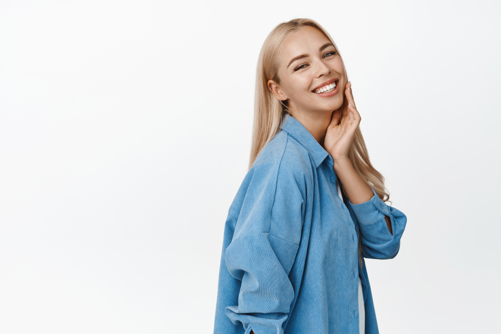 beautiful-blond-woman-with-glowing-healthy-skin-smiling-happy-camera-touching-her-face-enjoy-softness-standing-white-background.jpg